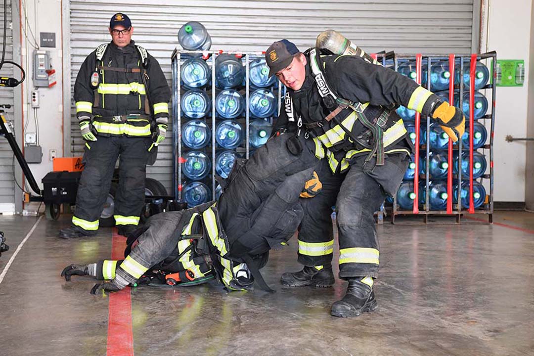Firefighters Hunter Holman and Zach Ayala demonstrate one method to carry a downed firefighter.